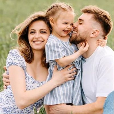 Eine glückliche Familie posiert in einem Feld: Mutter, Vater und ein lächelndes Kind.