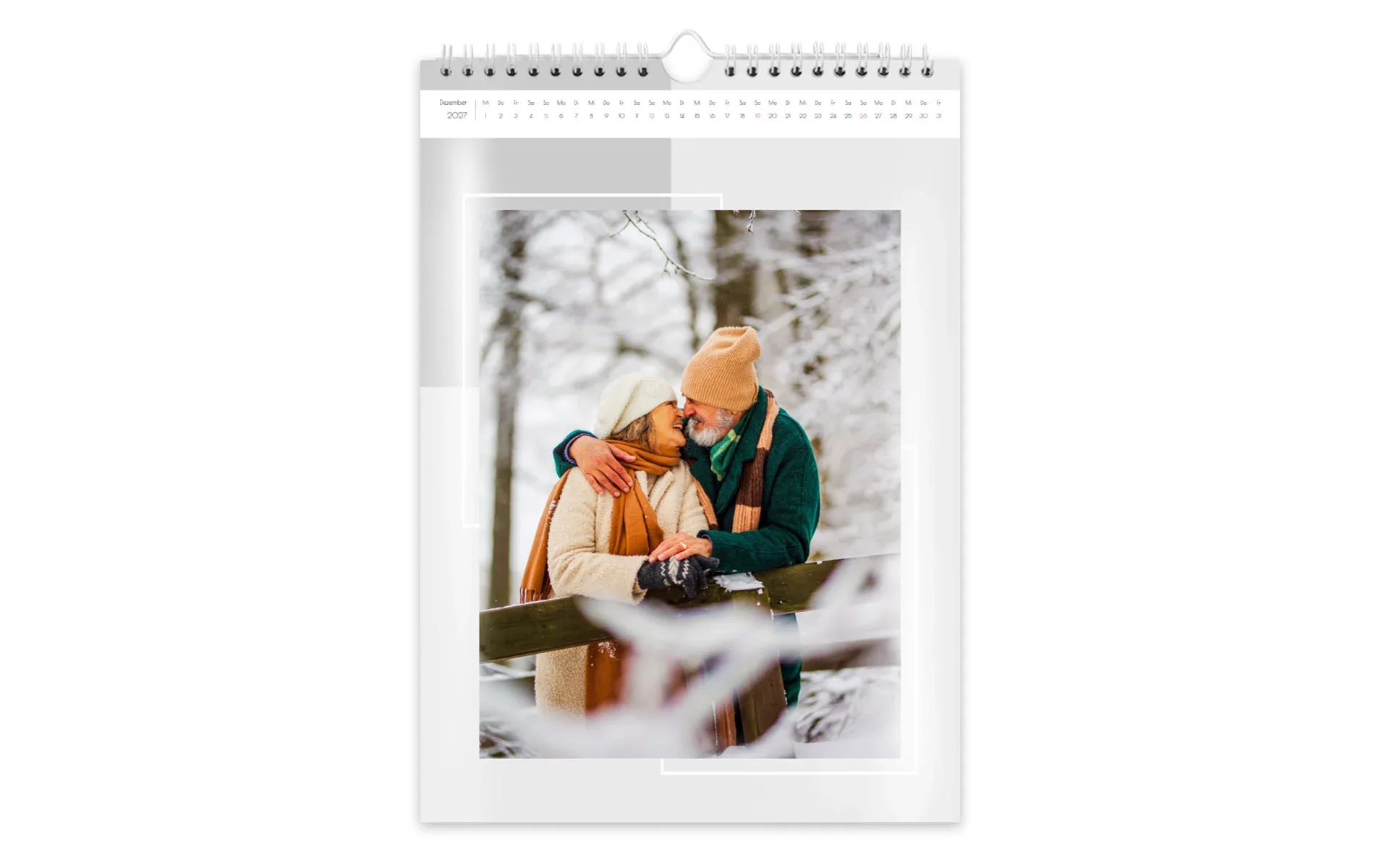 Ein HappyFotokalender ca. A3 hoch zeigt ein älteres Pärchen im verschneiten Wald vor grauem Hintergrund.