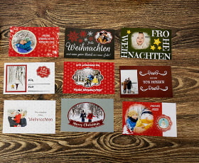 Verschiedene Weihnachtskarten mit festlichen Motiven und Grüßen auf einem Holztisch angeordnet.