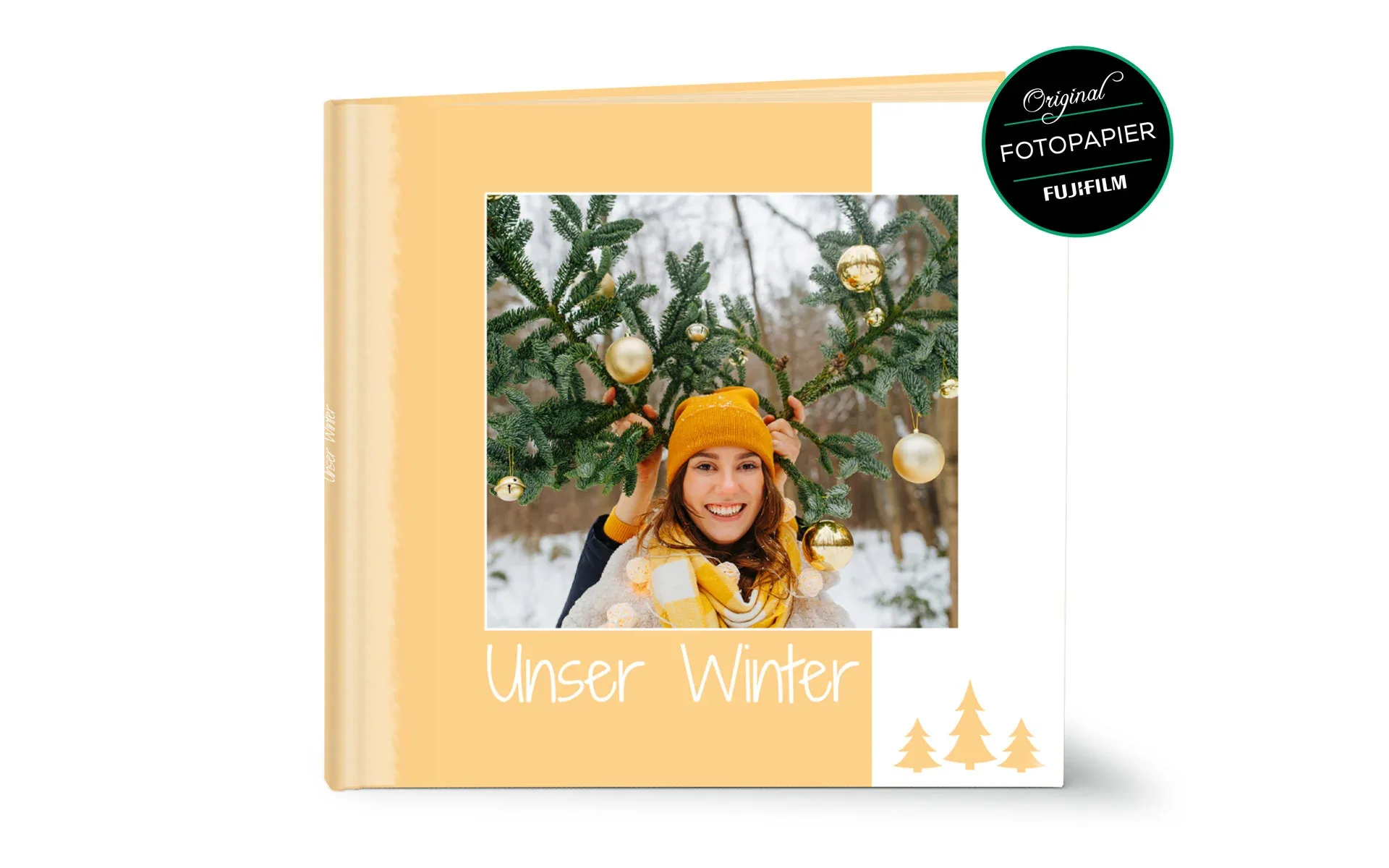 Happy Fotobuch ca. 30 x 30 cm Ein aufgestelltes Happy Fotobuch ca. 30 x 30 cm mit dem Titel Unser Winter zeigt ein eine Frau mit zwei Tannenzweige.