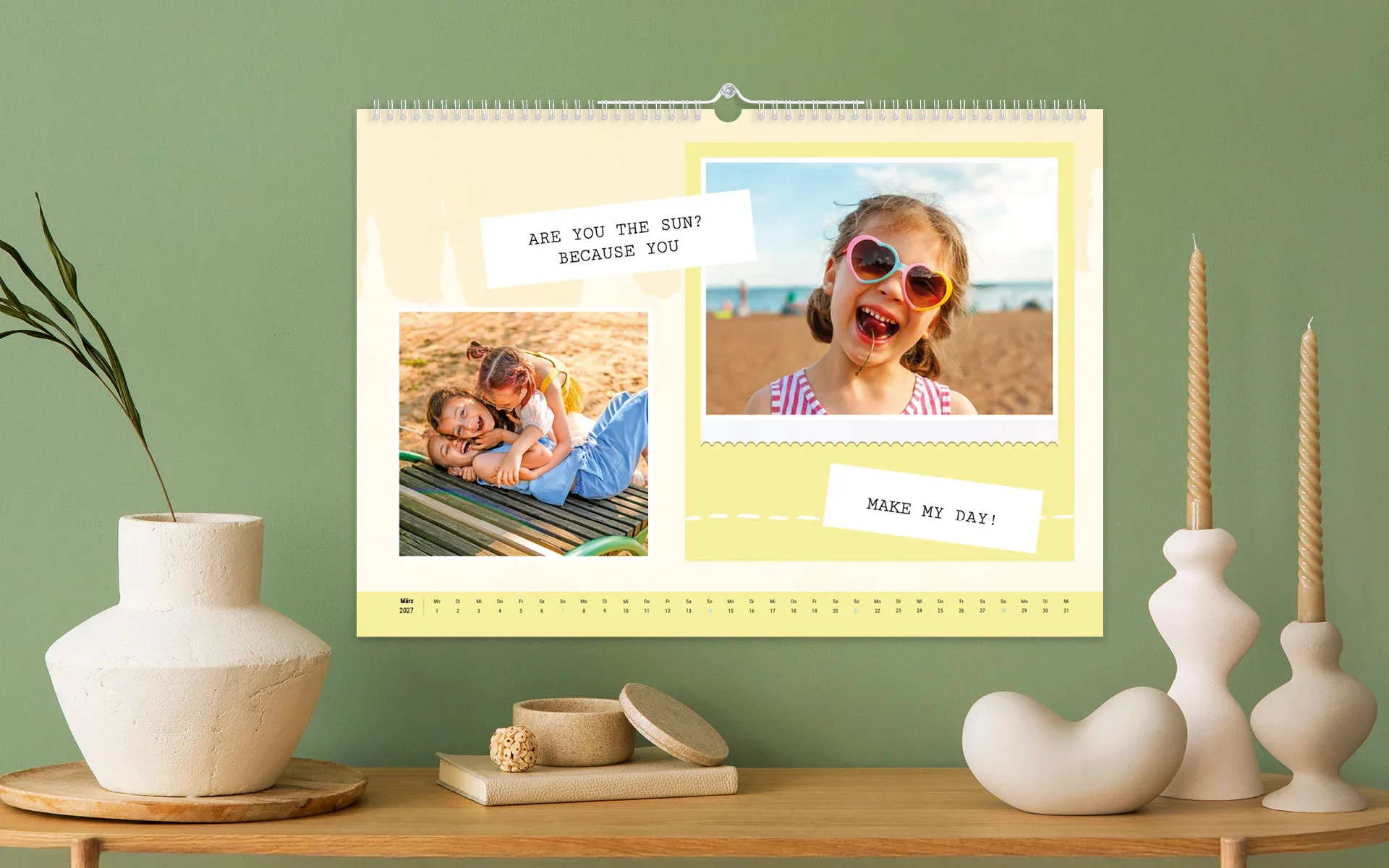 HappyFotokalender ca. A3 quer – aufgehängt Ein aufgehängter HappyFotokalender ca. A3 quer zeigt drei Mädchen am Strand vor gelbem Hintergrund.