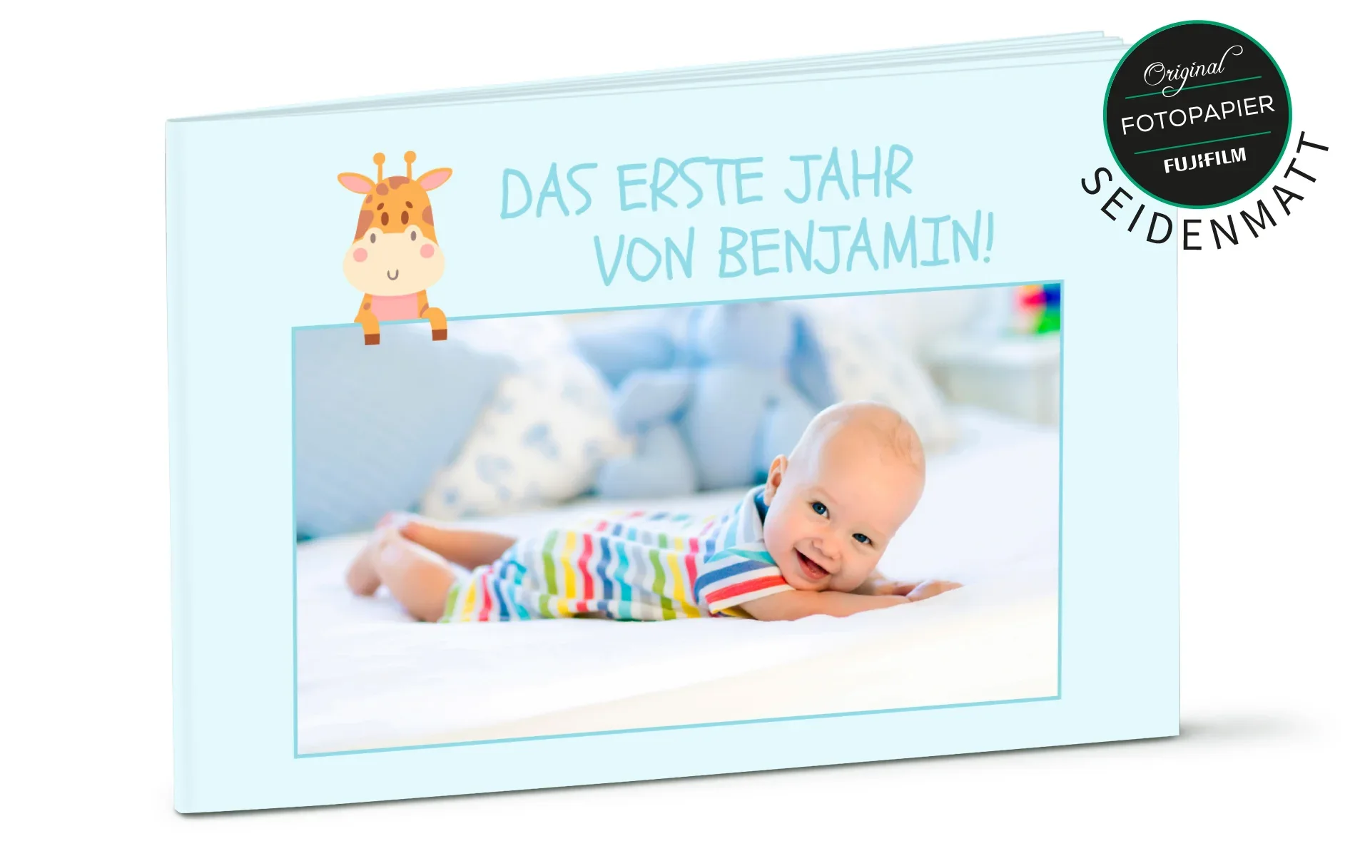 Ein aufgestelltes Happy Fotobuch ca. A4 hoch mit dem Titel Das erste Jahr von Benjamin zeigt ein Baby und ein Giraffen-Clipart.