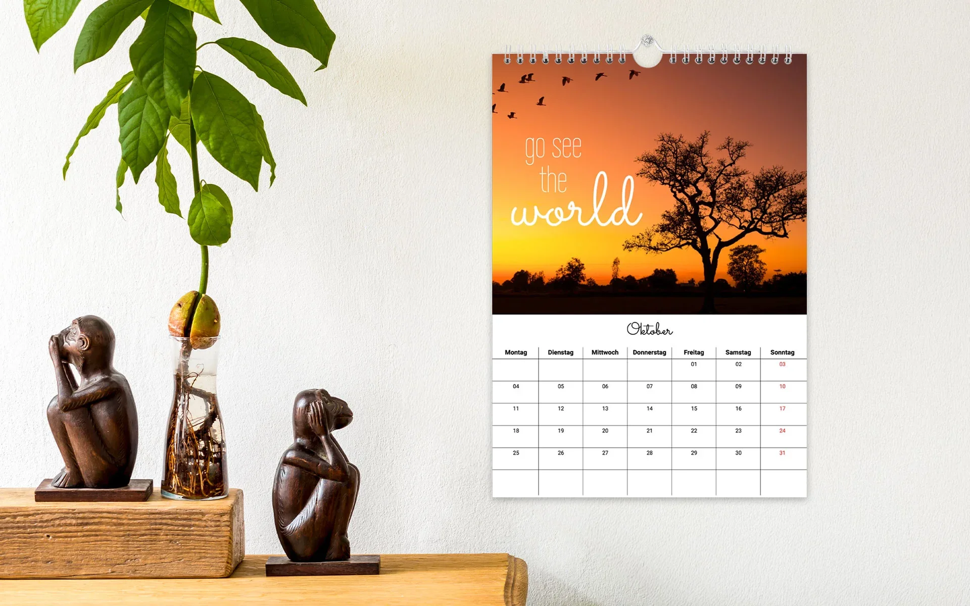 Ein aufgehängter HappyFotokalender ca. A4 hoch mit dem Text Go see the world zeigt 1 Foto von einem Sonnenuntergang.